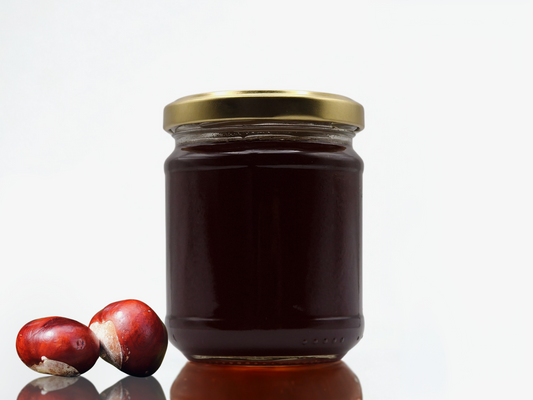 Pot de miel de châtaignier foncé avec deux châtaignes – couleur sombre, visuel brut et authentique.