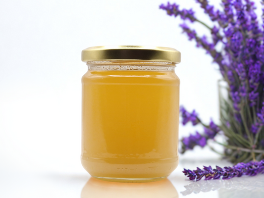 Pot de miel de lavande de Provence – couleur ambrée, texture fine, avec brins de lavande en arrière-plan.